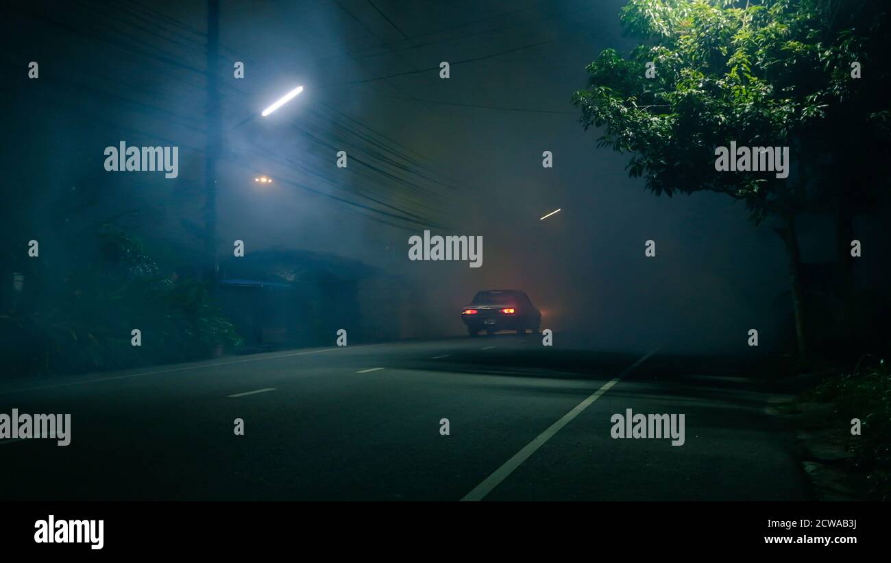 Auto classica guida in strada abbandonata con un grande gruppo di fumo e città fantasma concetto Foto Stock