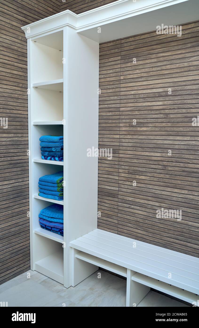 Armadio di legno bianco per asciugamani su parete di doghe di legno sfondo nello spogliatoio Foto Stock