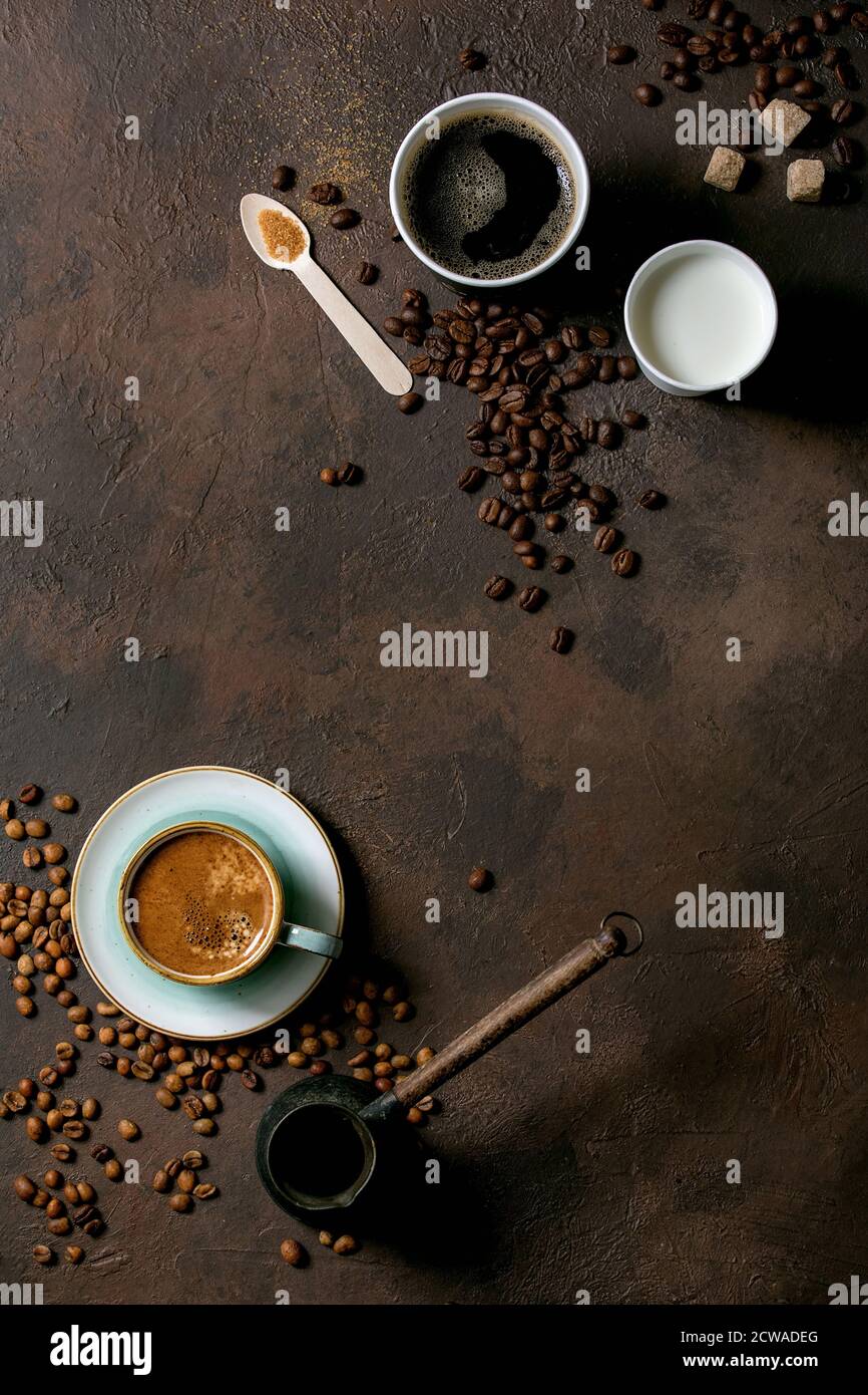 Varietà di tazze di carta di caffè americano e latte contro il caffè turco in tazza di ceramica e cezve, cucchiaio di legno riciclato di zucchero di canna, caffè in grani o Foto Stock