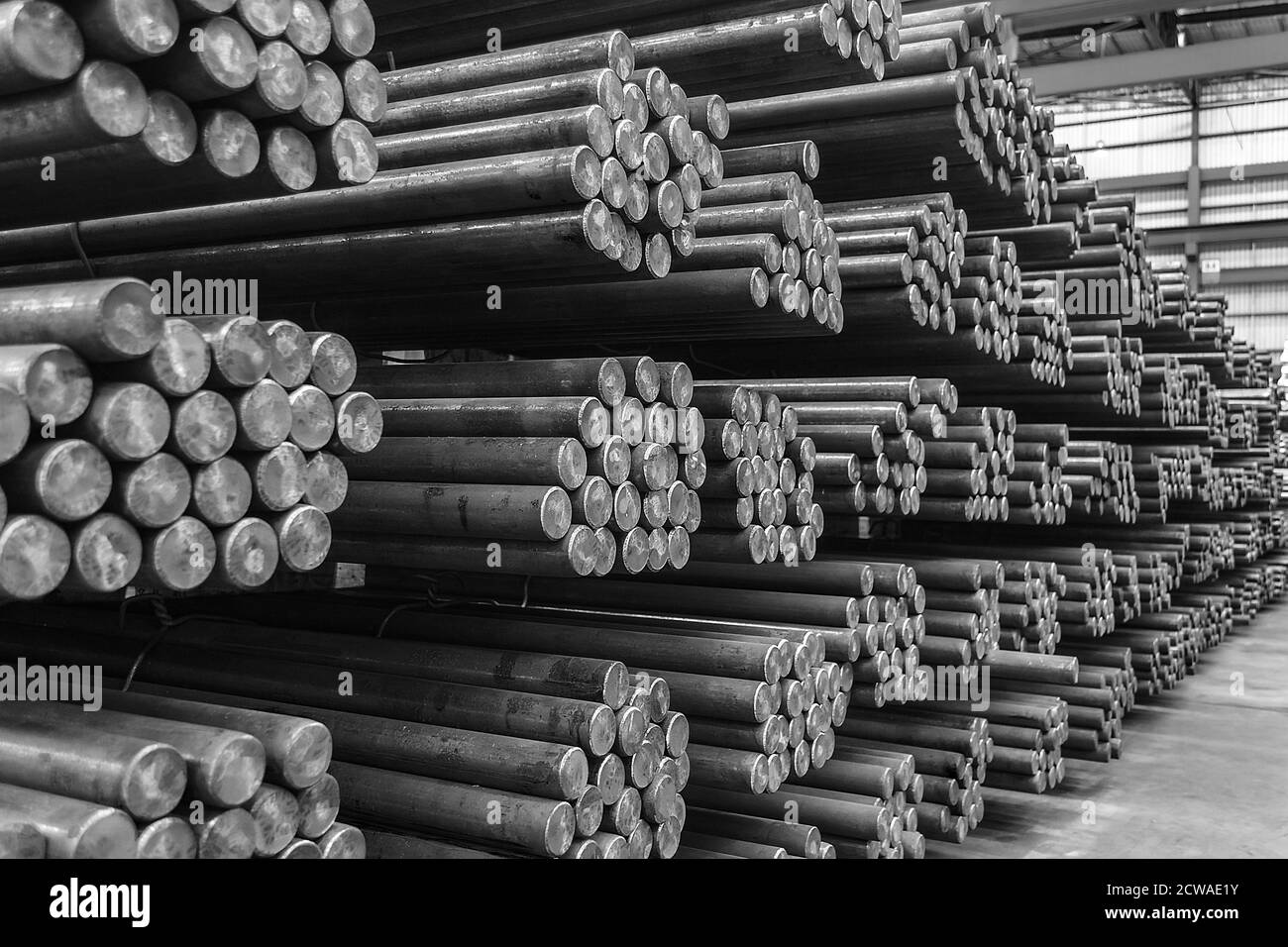 Stoccaggio e impilamento di barre tonde in acciaio in un magazzino. Foto Stock
