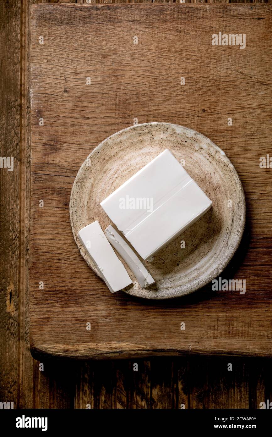 Tofu di seta giapponese formaggio di soia pezzo intero su piatto di ceramica con bastoni su tavolo di legno. Disposizione piatta, spazio Foto Stock