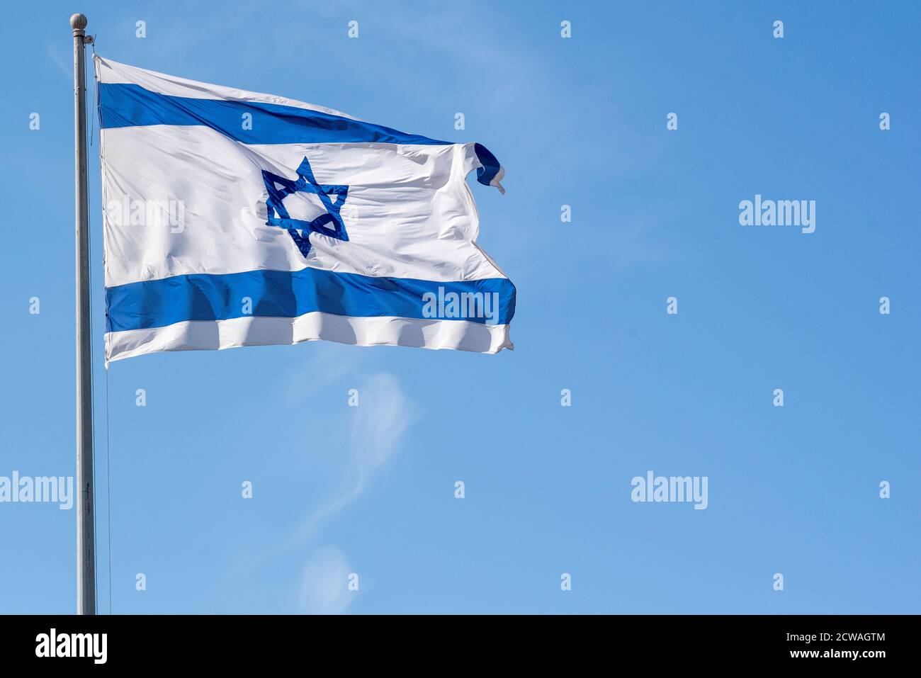 Bandiera israeliana blu e bianca soffia nel vento con uno sfondo blu Foto Stock