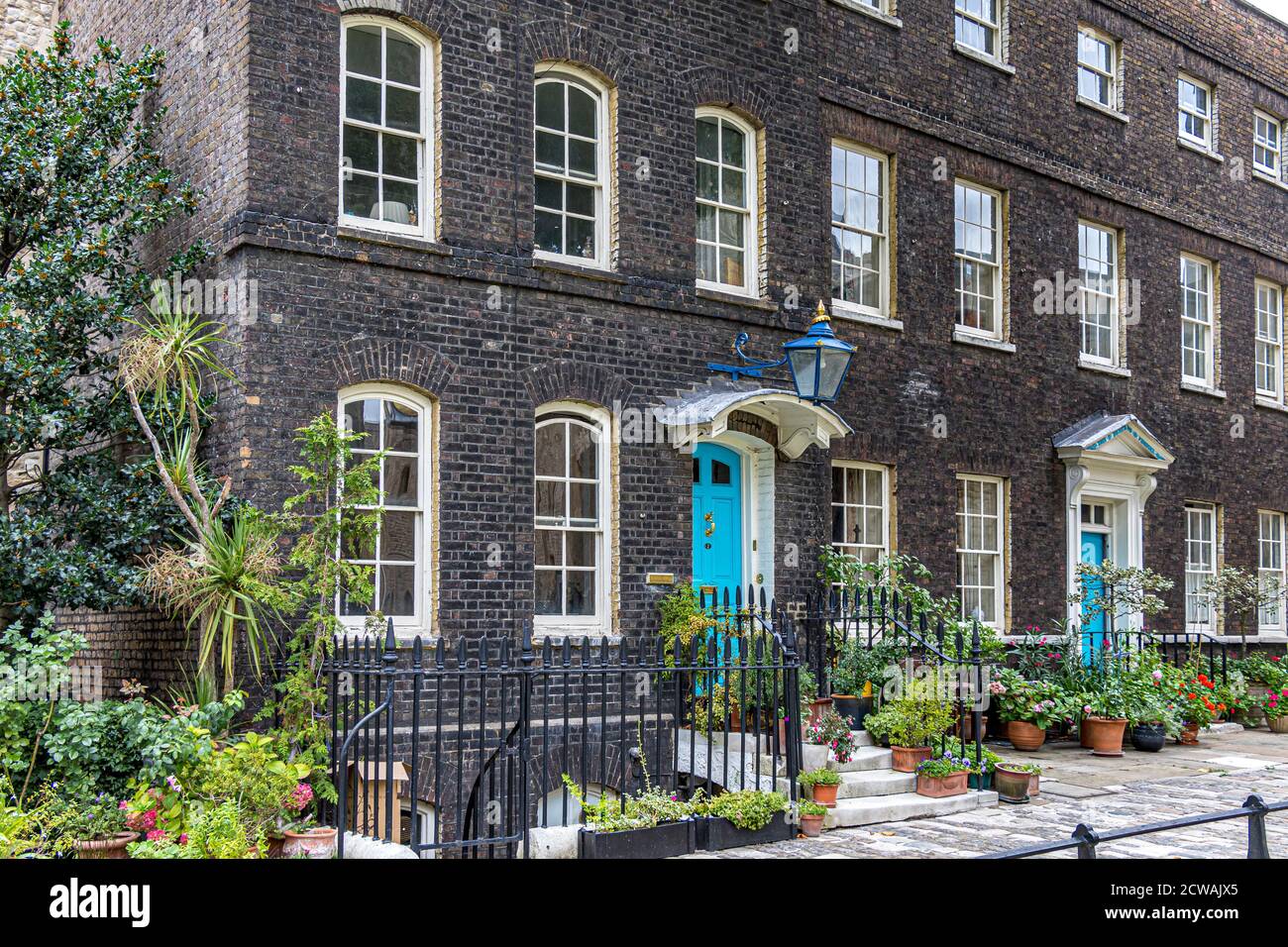 Elegante fila di case con recinzioni in metallo e porte blu di fronte a Tower Green, Torre di Londra, Londra EC3 Foto Stock