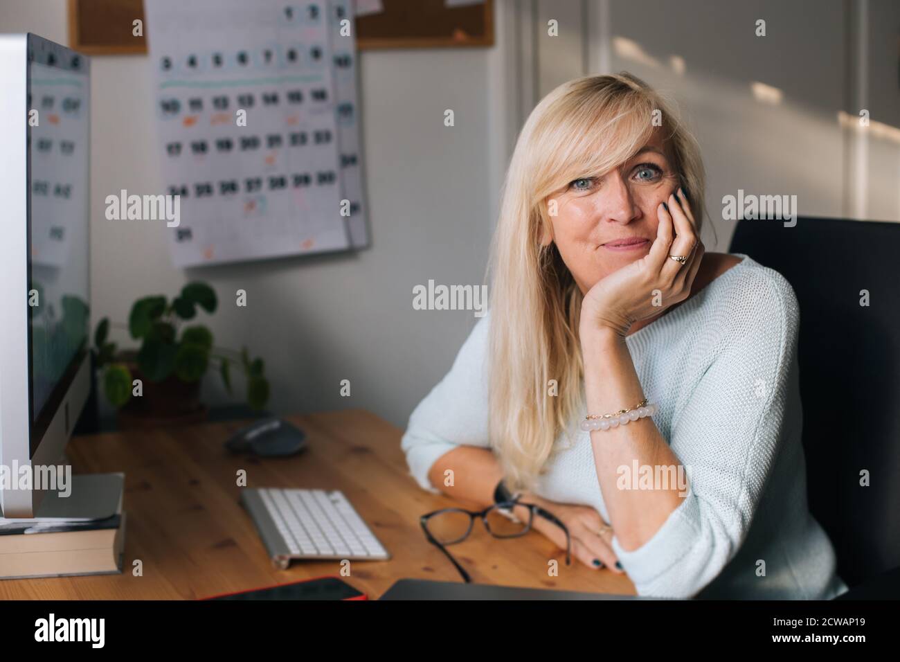 Ritratto di donna matura sorridente che lavora al computer nel suo ufficio domestico. Lavorare da casa imprenditore femminile seduto alla sua scrivania. Foto Stock