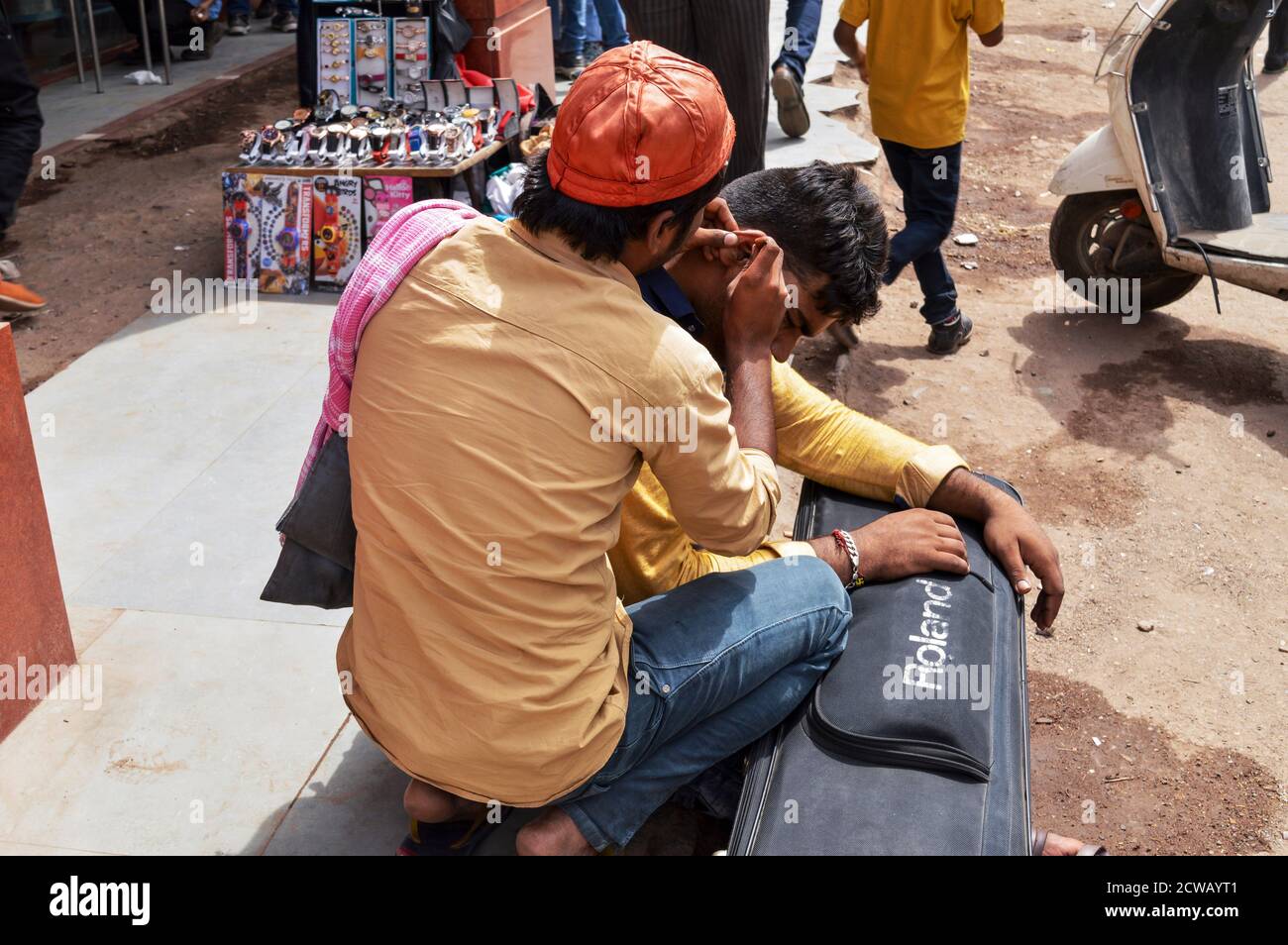 Un uomo sta pulendo l'orecchio del cliente, cera d'orecchi per soldi sulla strada trafficata in chandani chowk, vecchia delhi, india. Foto Stock