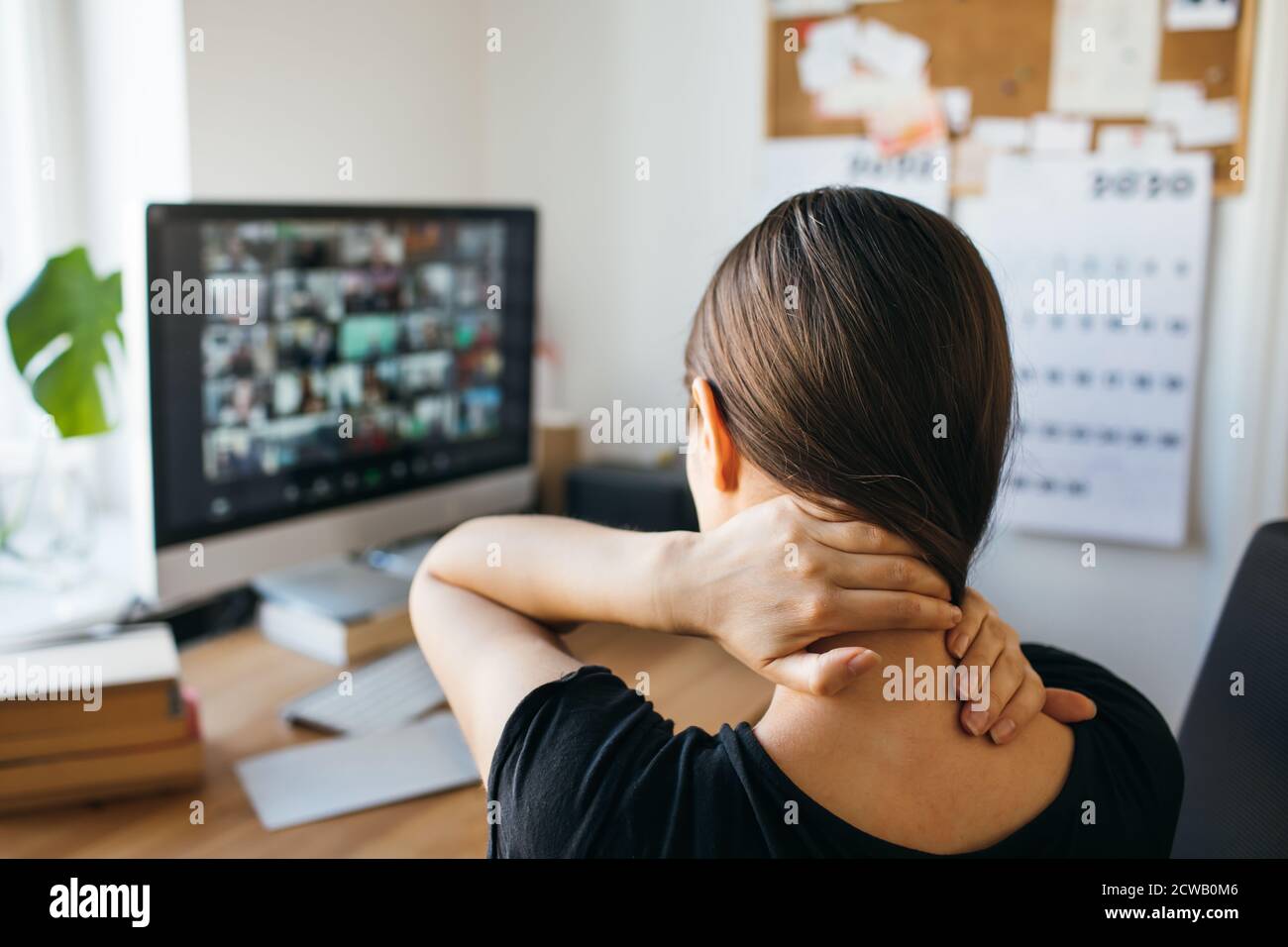 Giovane donna con dolore al collo dopo lunghe ore di lavoro in ufficio a casa. Allentare la tensione del collo. Foto Stock