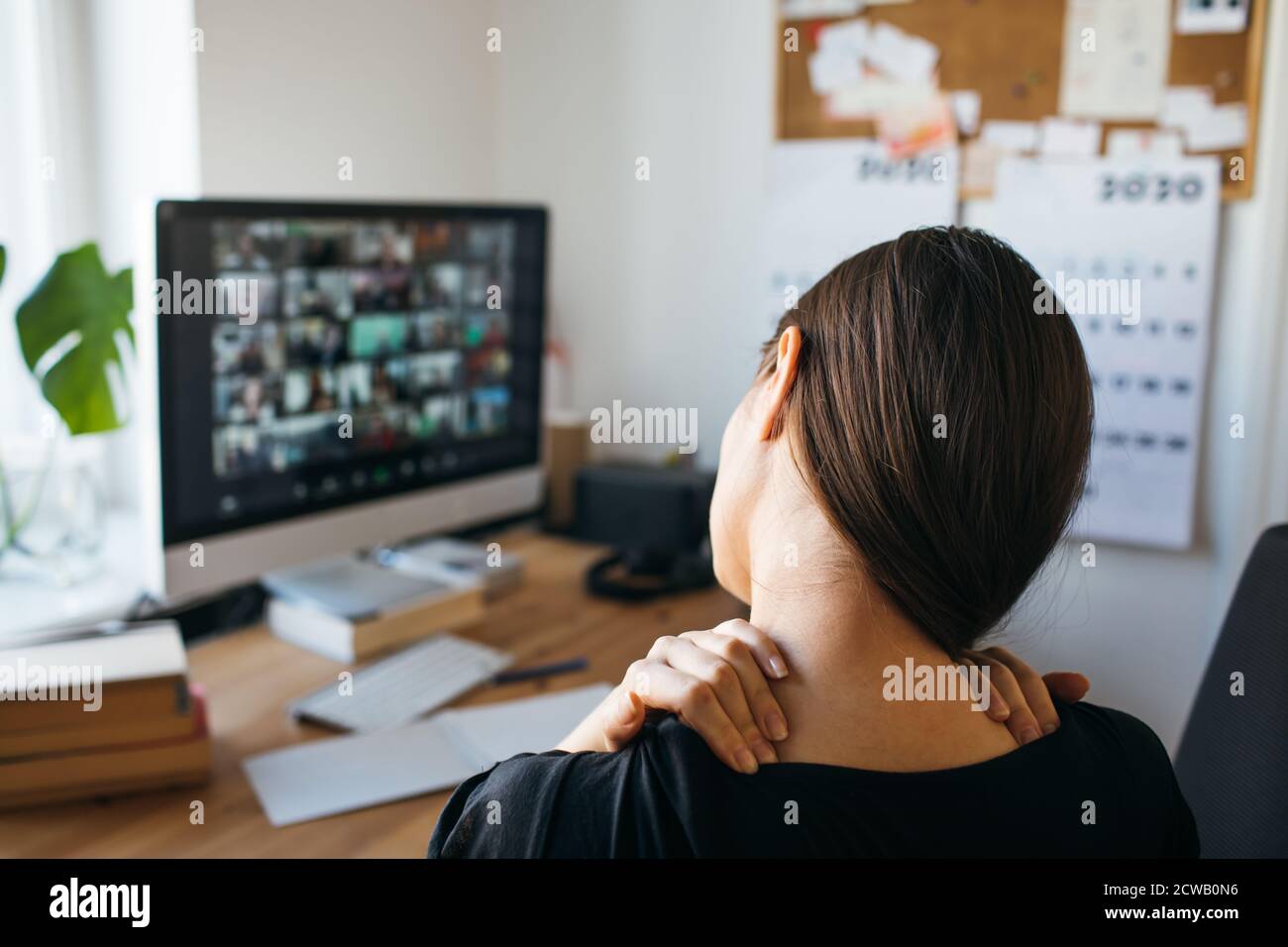Giovane donna con dolore al collo dopo lunghe ore di lavoro in ufficio a casa. Allentare la tensione del collo. Foto Stock