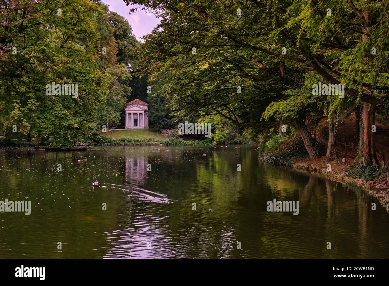 Alberi e un piccolo tempio neoclassico che si riflette in un laghetto boscoso nel parco di Monza, Lombardia, Italia Foto Stock