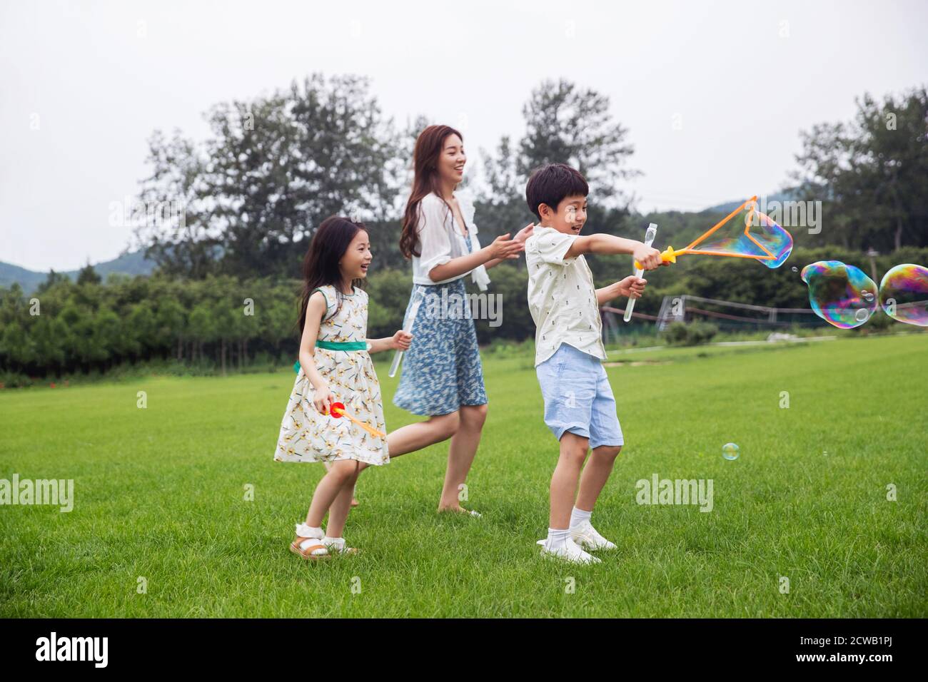 Madre con due bambini felice di giocare sul prato Foto Stock