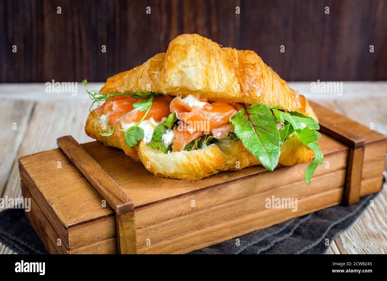 Delizioso croissant alle calorie con salmone, formaggio di cagliata ed erbe aromatiche. Foto Stock