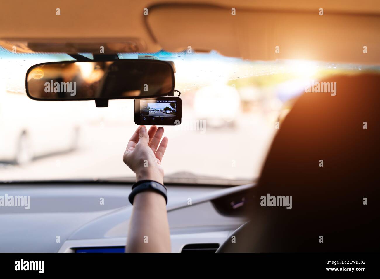 Registratore per auto con telecamera anteriore, videoregistratore da donna accanto a uno specchietto retrovisore Foto Stock
