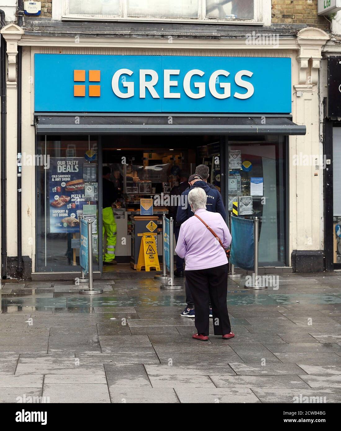 La gente coda di distanza sociale ad un negozio di Greggs a Slough, come la città di Berkshire è stata rimandata sulla lista di controllo del governo a causa di un aumento dei casi di coronavirus. Foto Stock