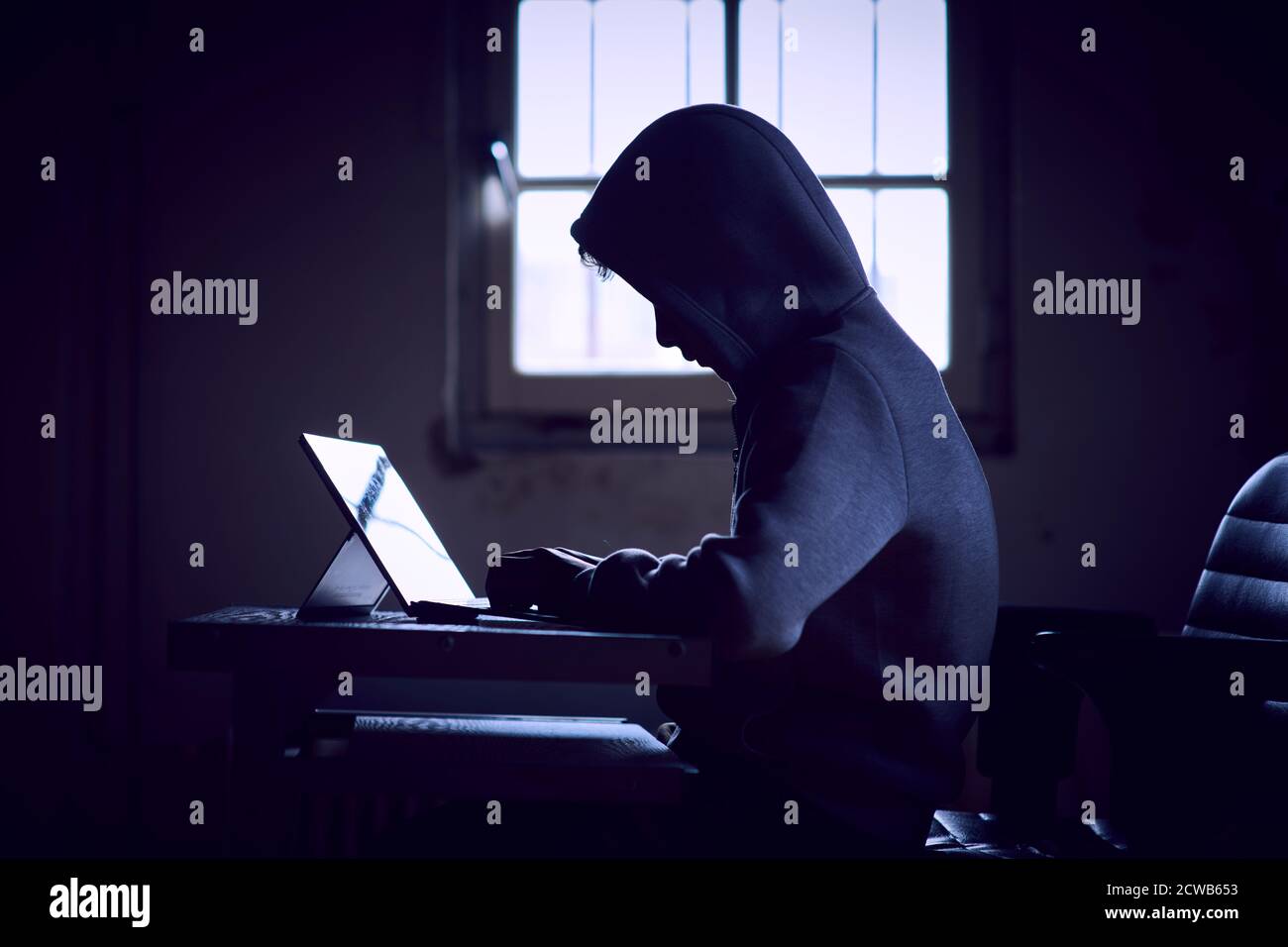 Computer hacker con felpa con cappuccio dietro il suo computer Foto Stock