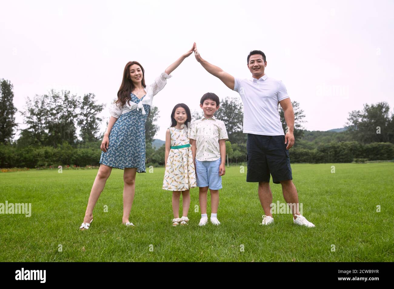 La gioia di una famiglia di quattro persone che si trova sul erba Foto Stock