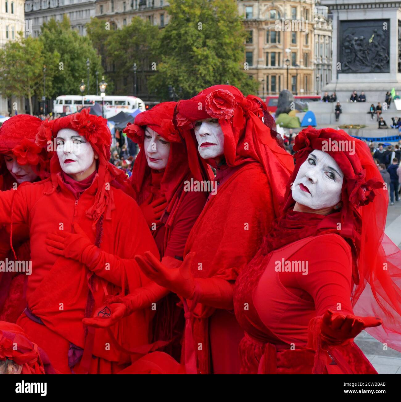 Il Circo invisibile alla ribellione estinzione protesta il 13 ottobre 2019, a Trafalgar Square nel centro di Londra . Il gruppo Invisible Circus di Bristol è composto da artisti di strada vestiti con abiti rossi che simboleggiano il sangue che lega l'umanità insieme. Foto Stock