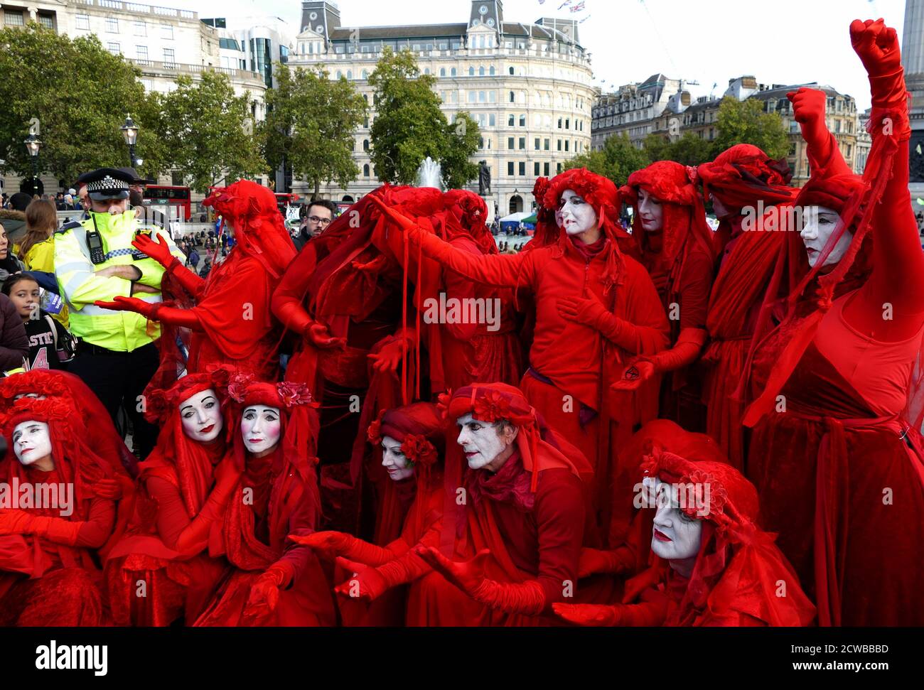 Il Circo invisibile alla ribellione estinzione protesta il 13 ottobre 2019, a Trafalgar Square nel centro di Londra . Il gruppo Invisible Circus di Bristol è composto da artisti di strada vestiti con abiti rossi che simboleggiano il sangue che lega l'umanità insieme. Foto Stock