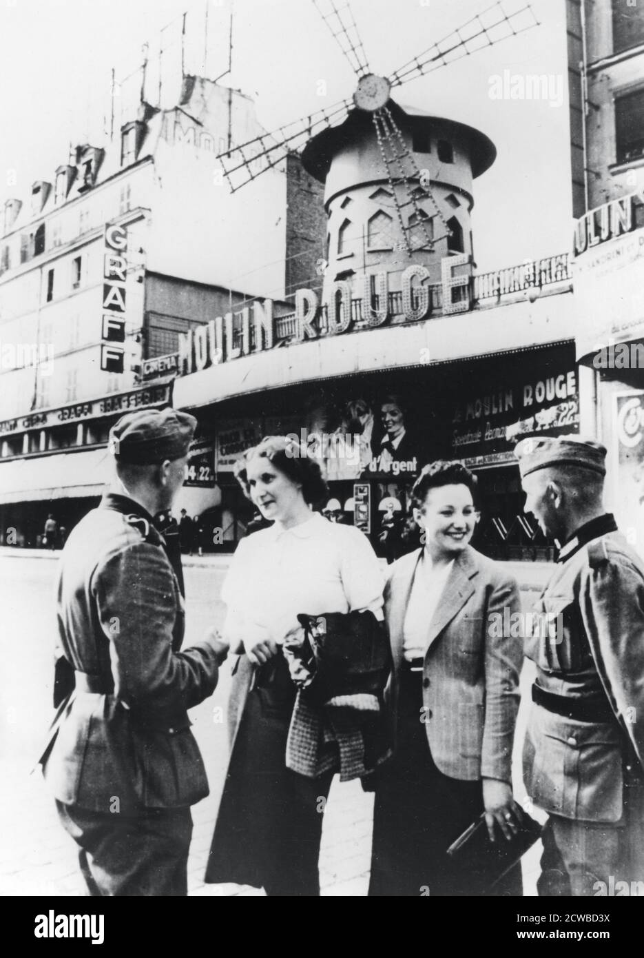 Soldati tedeschi che parlano con le donne francesi fuori del Moulin Rouge, a Parigi occupata, 1940 giugno. Il fotografo è sconosciuto. Foto Stock