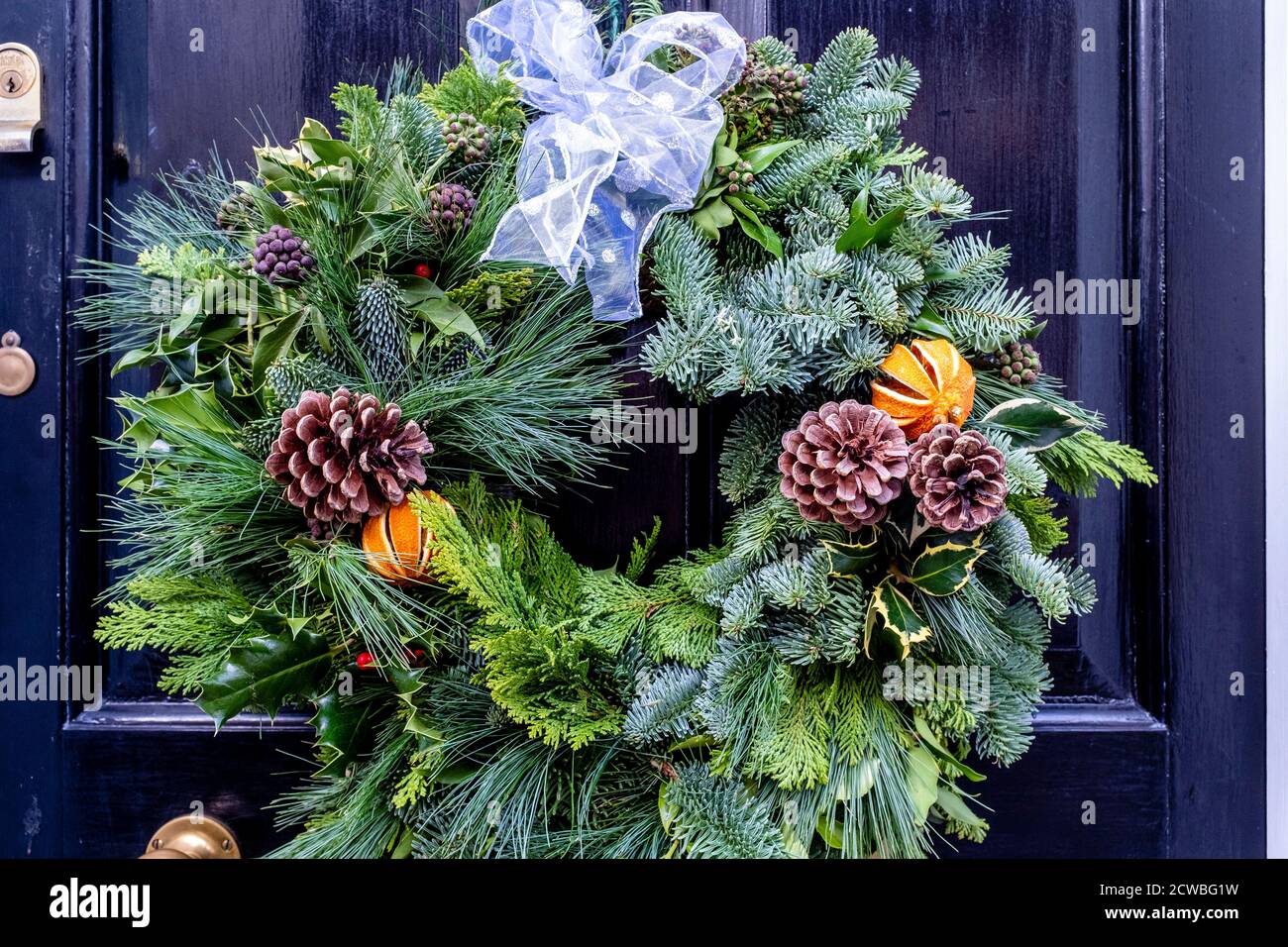Una corona di Natale che si aggira su UNA porta, High Street, Lewes, East Sussex, UK. Foto Stock