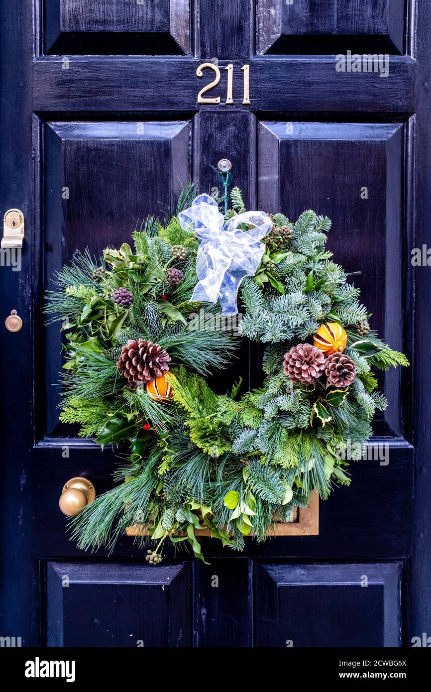 Una corona di Natale che si aggira su UNA porta, High Street, Lewes, East Sussex, UK. Foto Stock