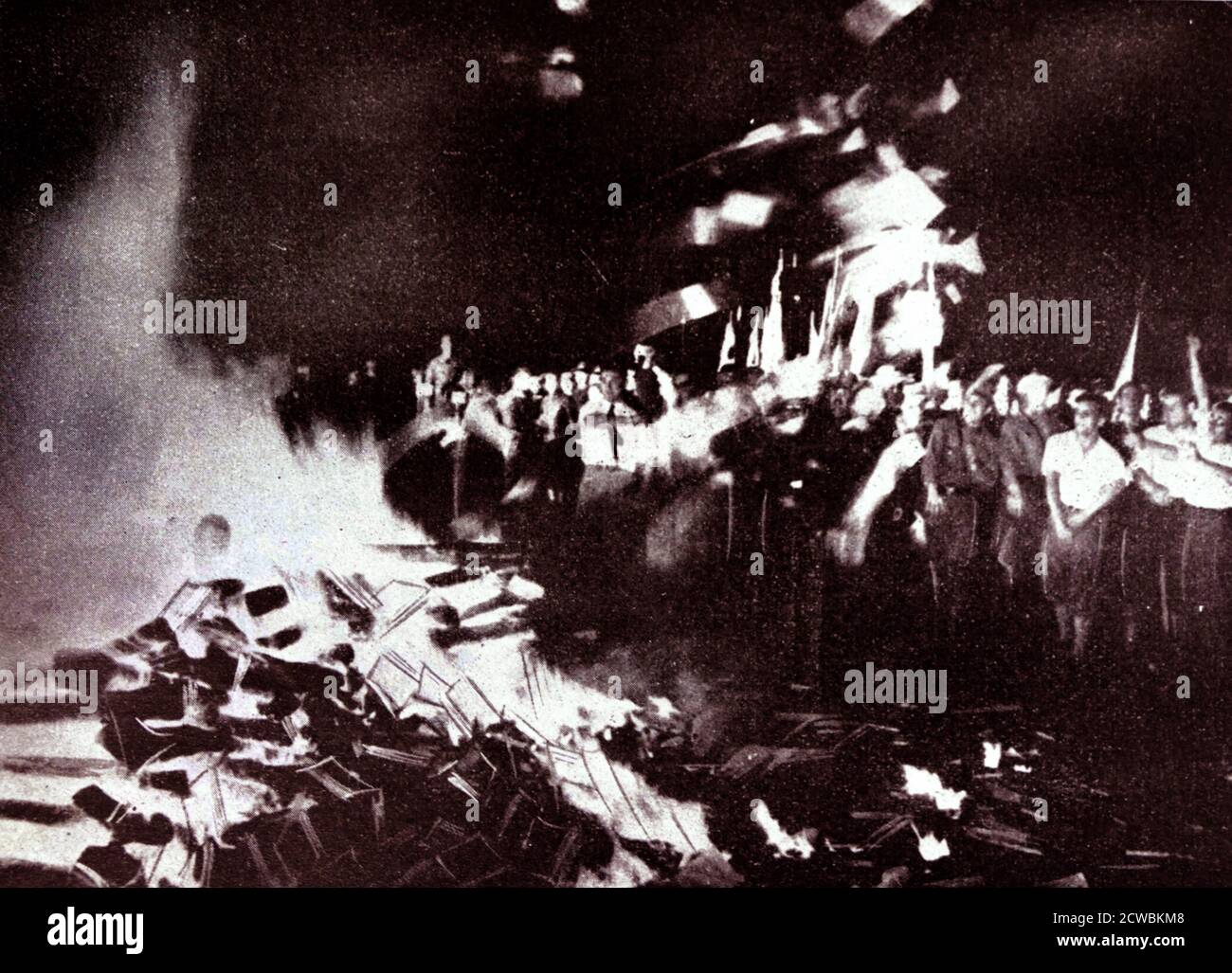 Foto in bianco e nero di un grande falò in cui una folla frenetica lancia milioni di volumi dalle biblioteche pubbliche che il regime di Hitler ha condannato come "non tedesco". Foto Stock