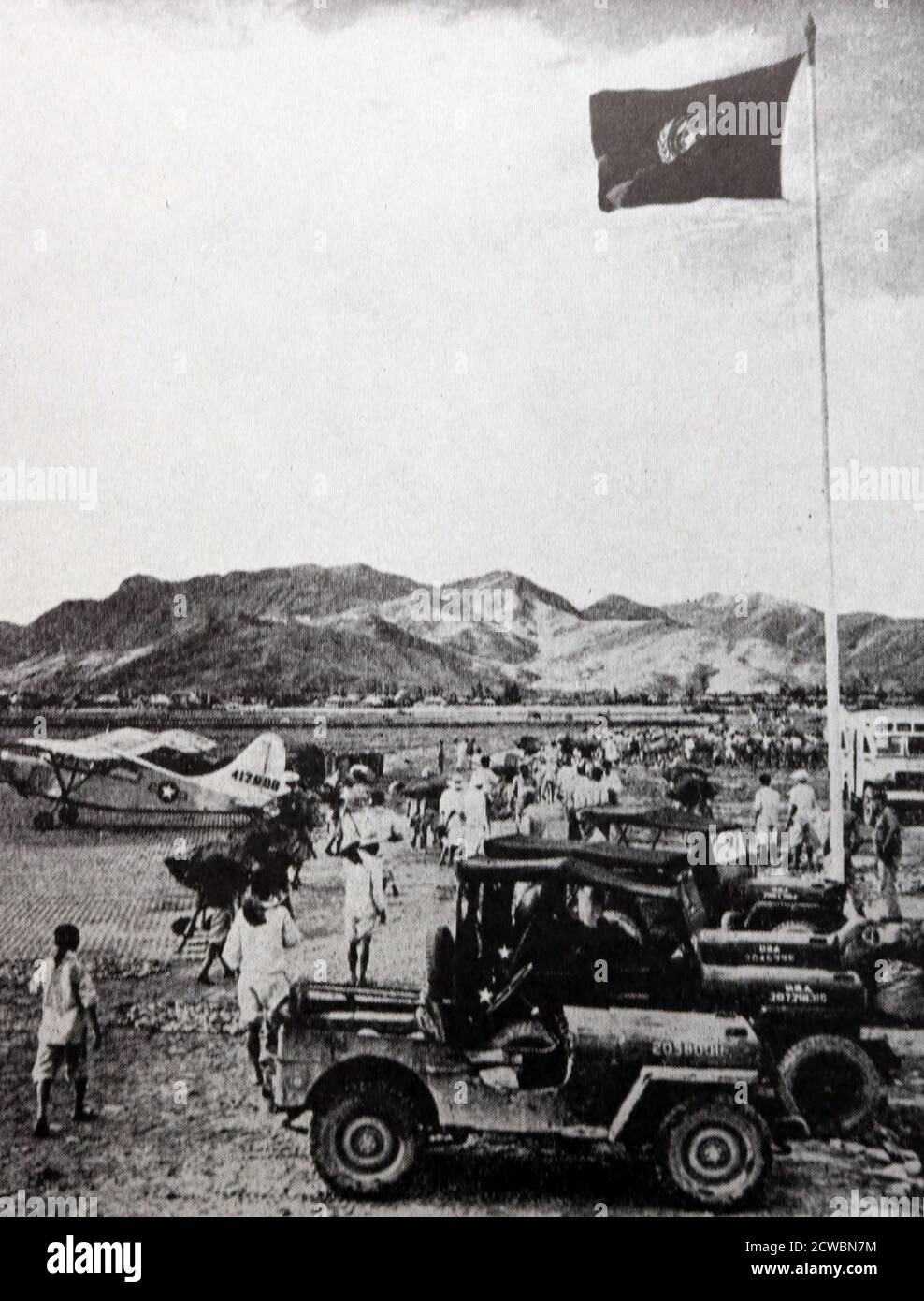 Fotografia in bianco e nero della guerra di Corea (1950-1953); una bandiera con i colori delle Nazioni Unite vola su un campo d'aviazione. Foto Stock