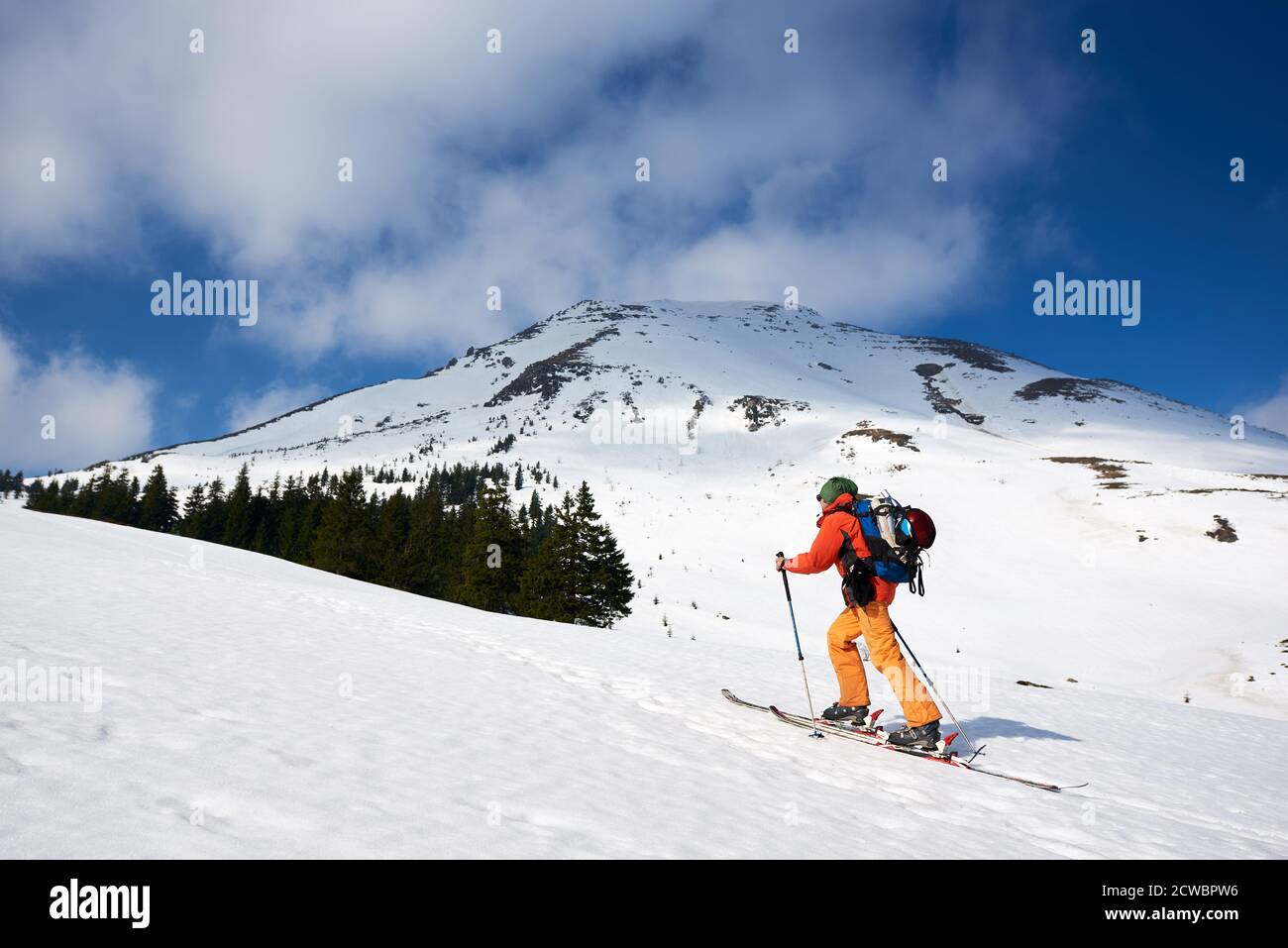 Uomo scialpinista che raggiunge la cima nelle spettacolari montagne innevate in giornata di sole. Neve e attività invernali, sciare in montagna. Foto Stock