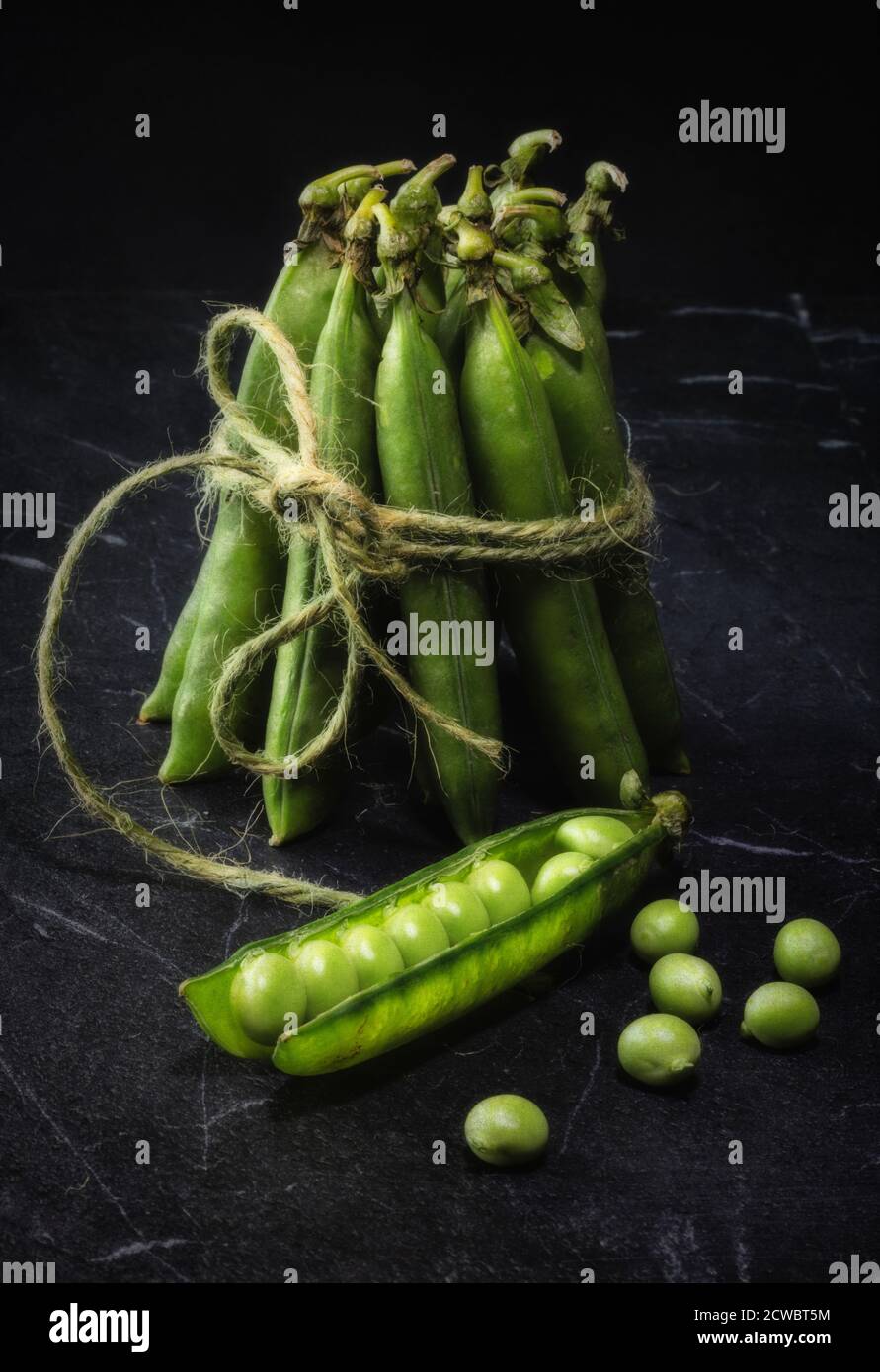 Un pacchetto di piselli freschi su marmo nero Foto Stock