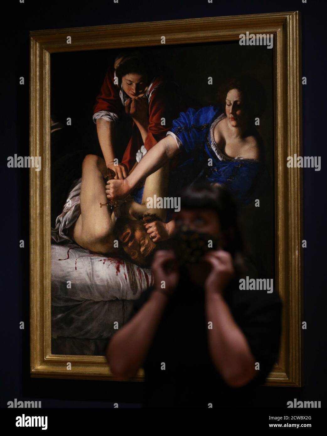 L'attore Ellice Stevens si pone accanto all'opera Judith che ha diretto Holofernes, circa 1612-13, del pittore barocco italiano Artemisia Gentileschi, durante una telefonata per vedere in anteprima la prossima mostra Artemisia di Londra della National Gallery. Foto Stock
