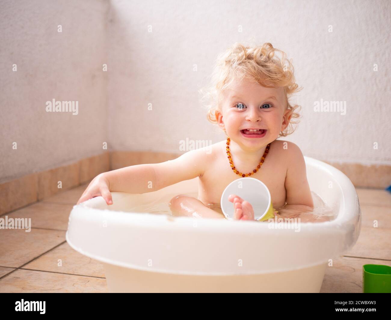Un bambino di un anno che si gode un bagno sul balcone Foto Stock