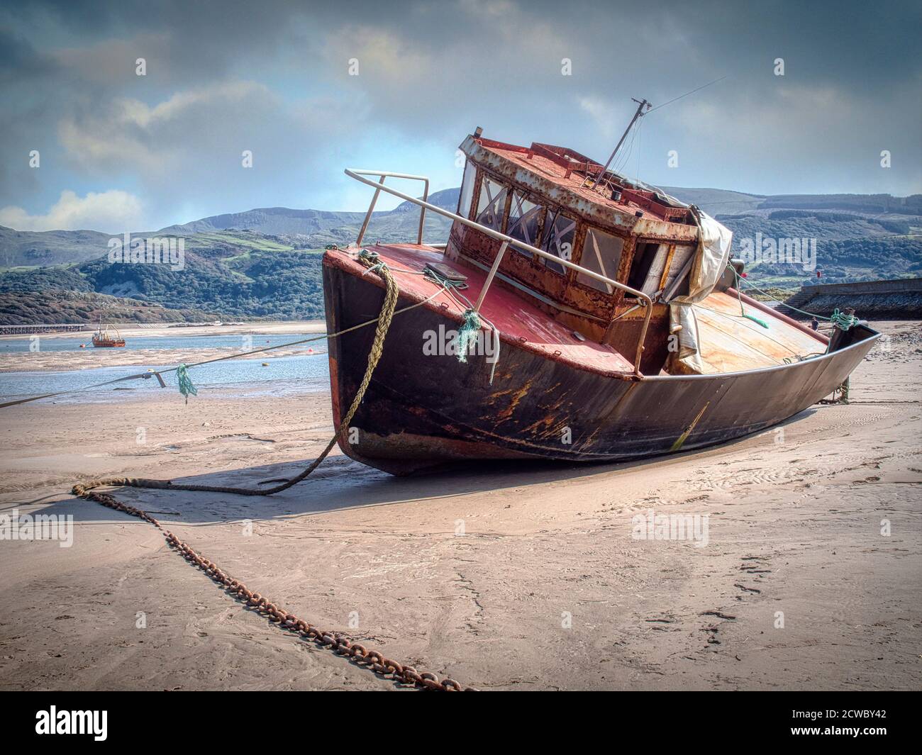 Spiaggia di Barmouth, Galles settentrionale, sede di una barca di pesca arrugginita Foto Stock