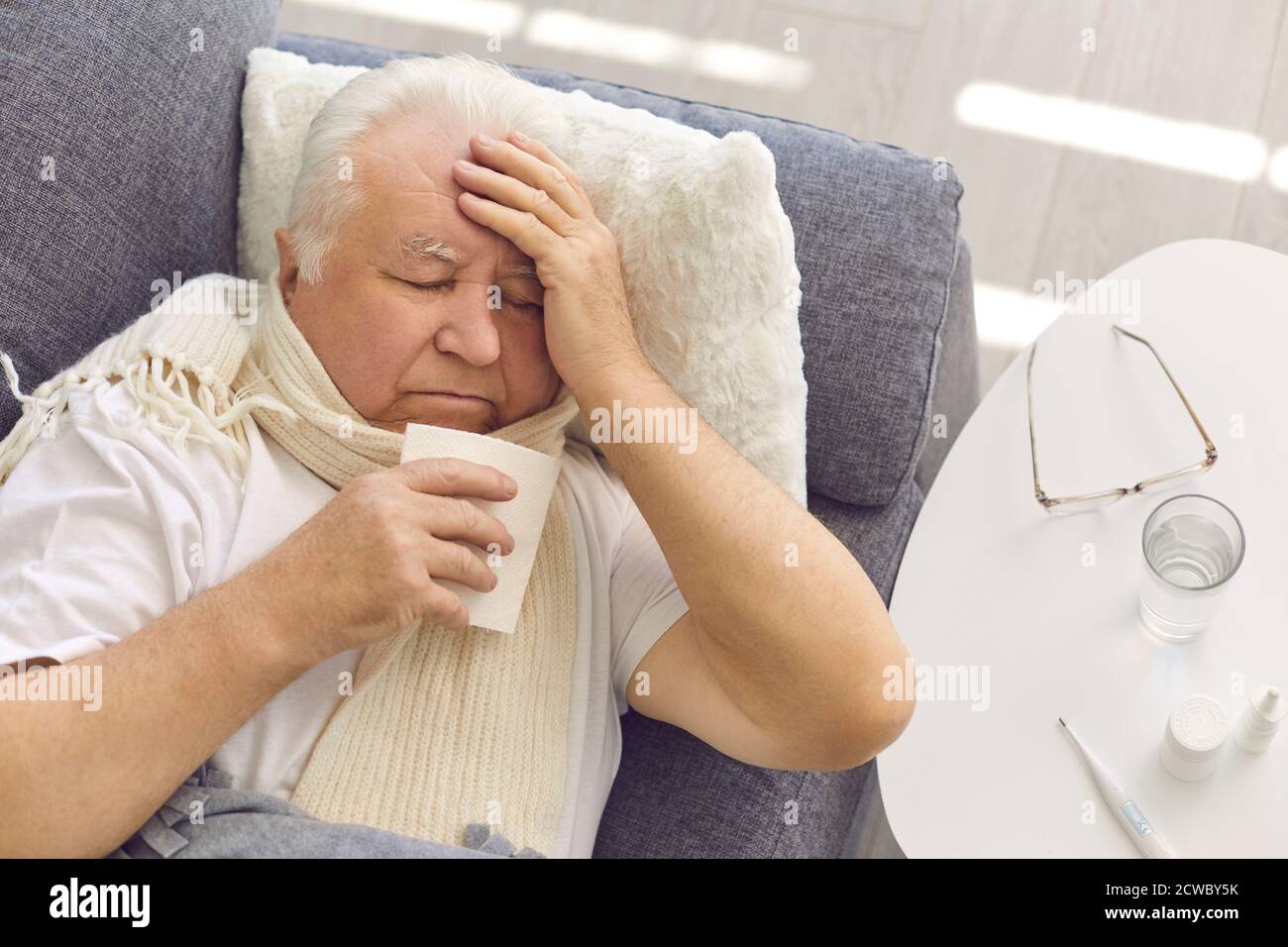 Uomo anziano che soffre di raffreddore, influenza o febbre coviale, tosse e naso che cola Foto Stock