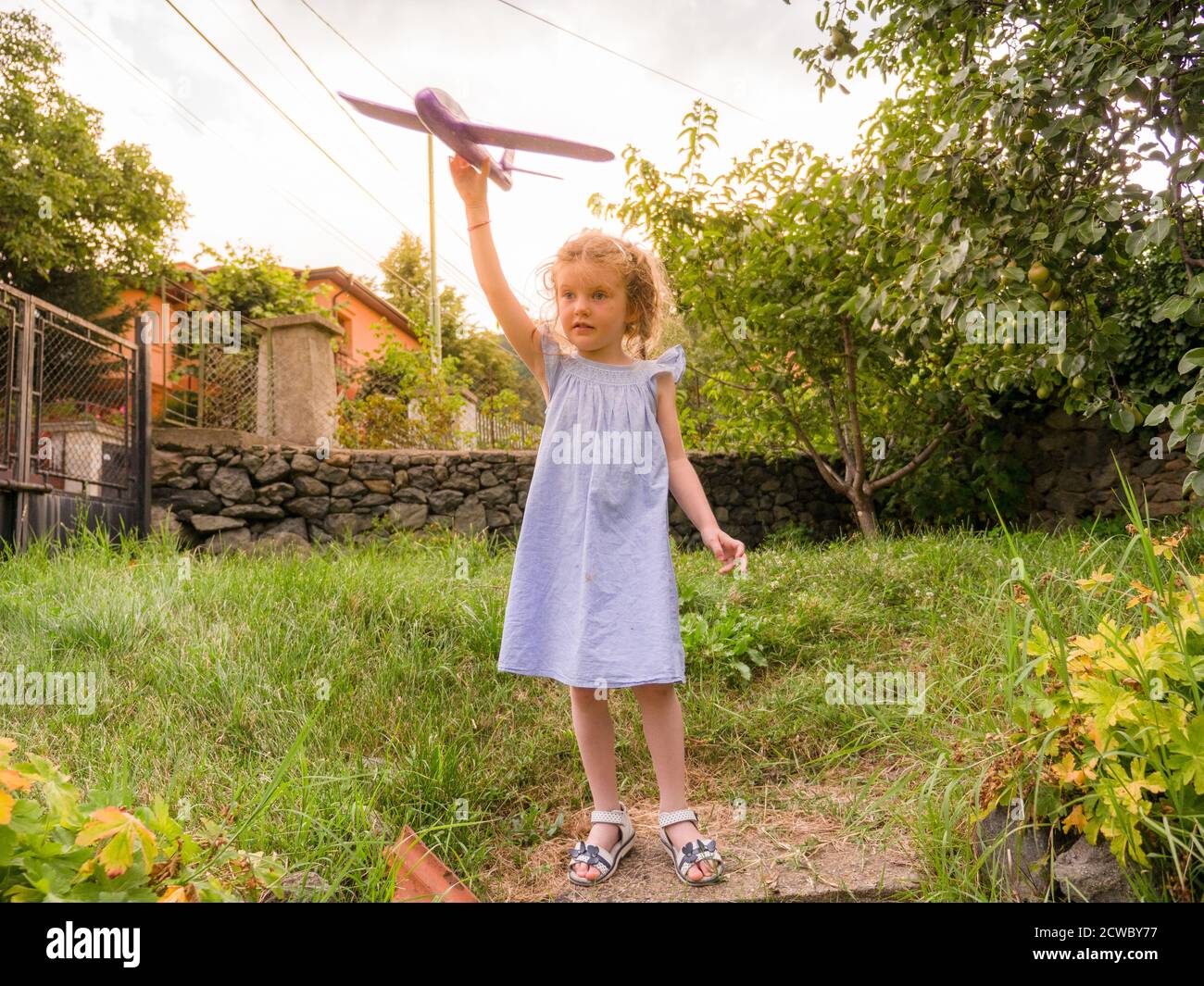 Felice giovane ragazza che vola aereo giocattolo all'aperto in giardino Foto Stock