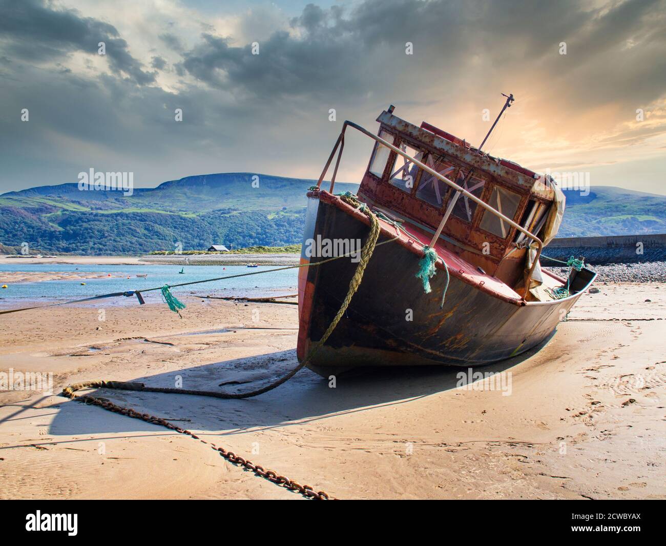 Spiaggia di Barmouth, Galles settentrionale, sede di una barca di pesca arrugginita Foto Stock
