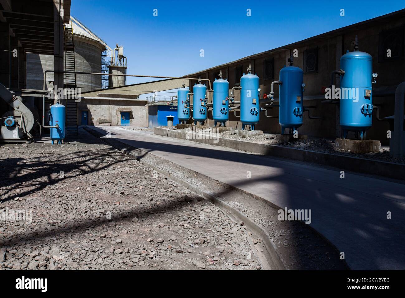 Impianto di cemento Jambyl. Stazione di purificazione e filtrazione dell'acqua. Serbatoi del filtro dell'acqua blu con valvole e tubi. Silo di cemento rotondo e cielo blu su bac Foto Stock