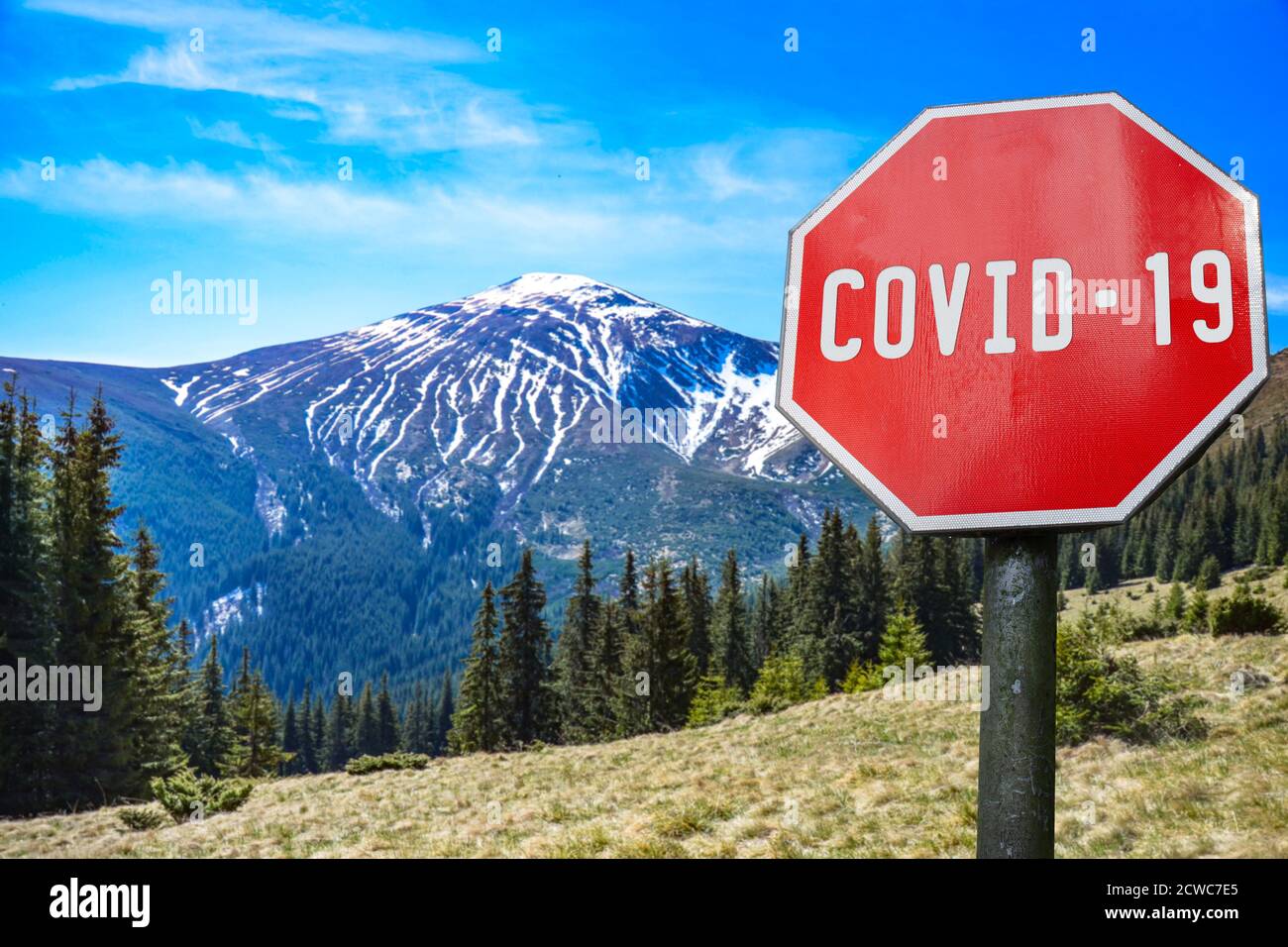 Gamma di montagne con il segno COVID-19. Avviso sulla pandemia globale. Malattia del coronavirus. Segnale di allarme COVID-19 Foto Stock