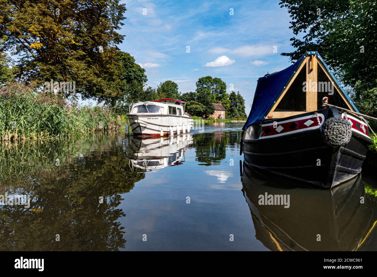 Staycation barca a motore River Wey estate, crociera a monte e tipica barca ormeggiata stretta in primo piano, Papercourt Lock cottage dietro Surrey UK Foto Stock