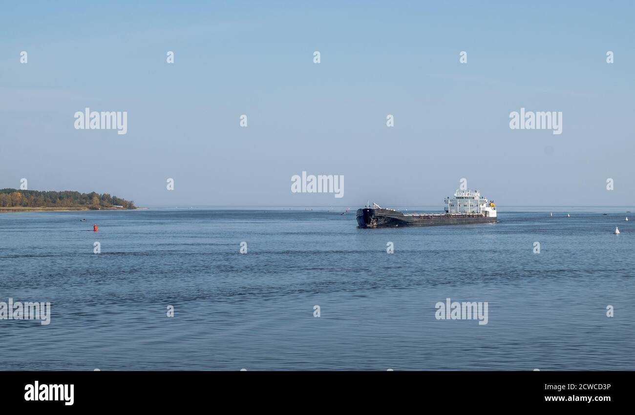 Una nave mercantile naviga nel fairway tra le boe su un grande lago o mare. Flotta marina, trasporto commerciale di merci. Orientamento orizzontale, Foto Stock