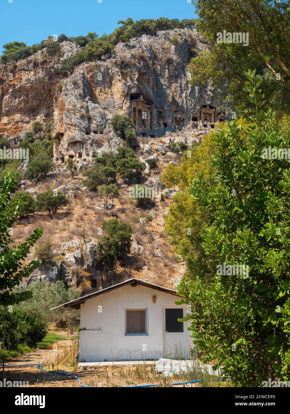 Antiche tombe rupestri dei Re Licia tagliate nella parete rocciosa sopra un moderno edificio del villaggio, Dalyan, Turchia Foto Stock