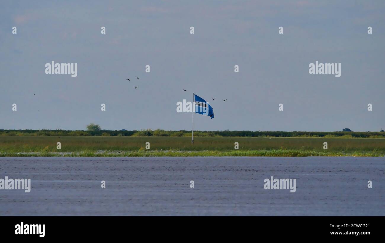 Kasane, Botswana - 04/29/2018: Bandiera nazionale del Botswana che svetta sopra l'isola fluviale Sedudu al confine tra Botswana e Namibia. Foto Stock