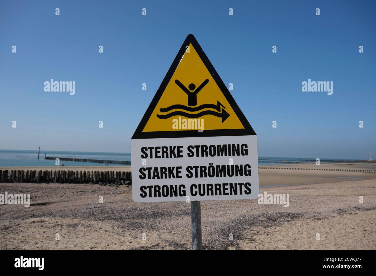 Forte segno di corrente sulla spiaggia con il mare blu nel sfondo Foto Stock