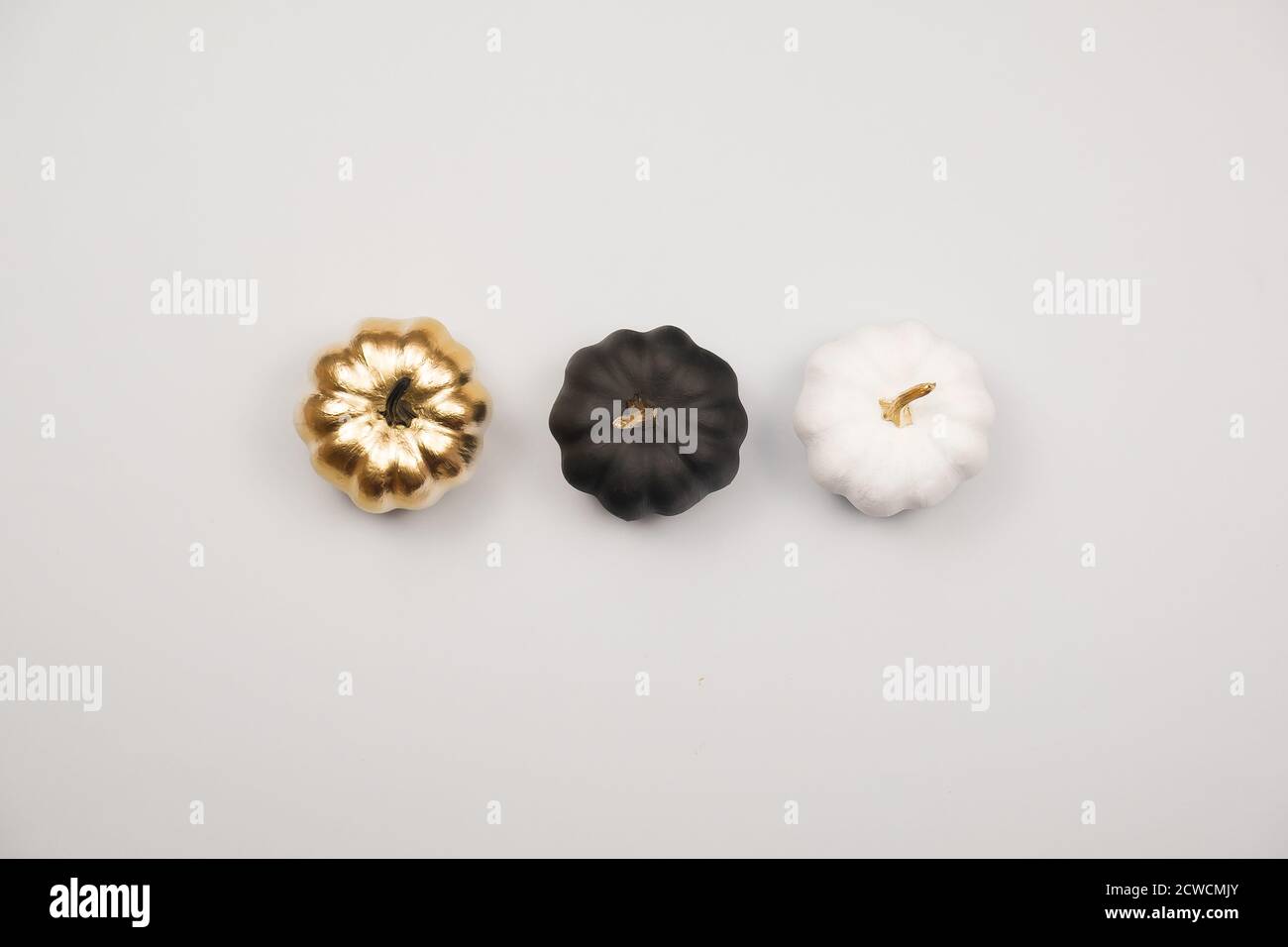 Concetto minimo di vacanza di Halloween. Decorazione di Halloween, zucche dorate, nere e bianche. Disposizione piatta, vista dall'alto, spazio per la copia Foto Stock