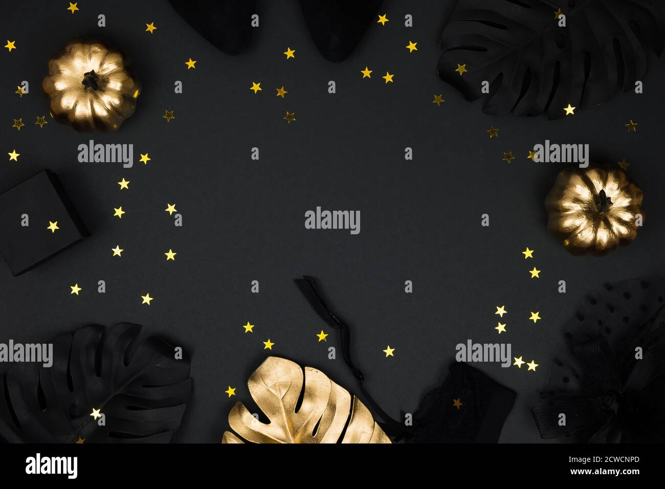 Halloween party collection accessori outfit femminile su sfondo nero: cappello con velo, cintura garter, regali. Zucche nere e dorate, piatto, top Foto Stock