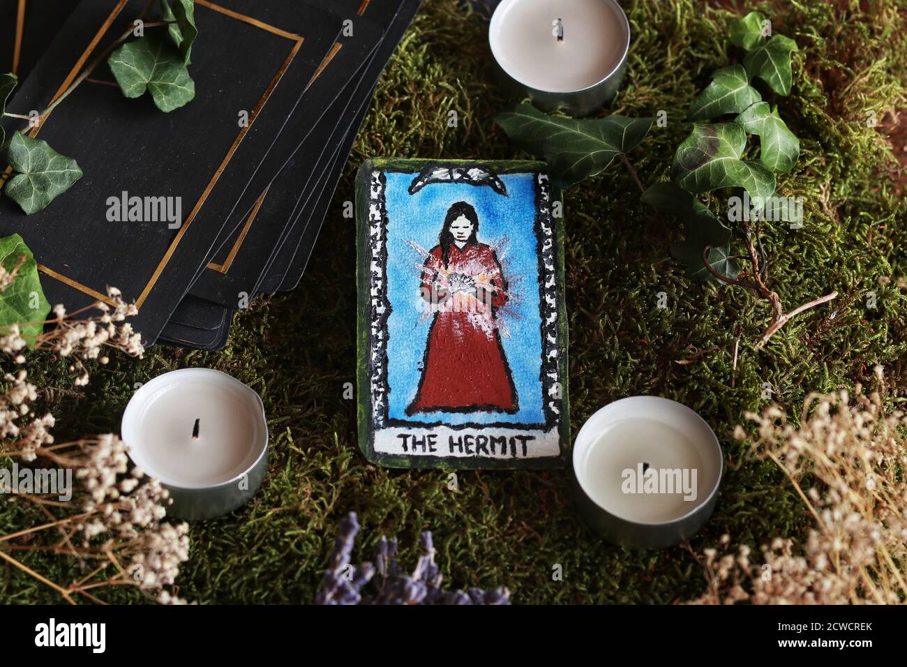 Scheda tarocchi dipinta a mano (non reale) l'Eremita sull'altare verde delle streghe di wiccan. Disposizione piatta di una scheda posta sullo sfondo di muschio verde della foresta Foto Stock