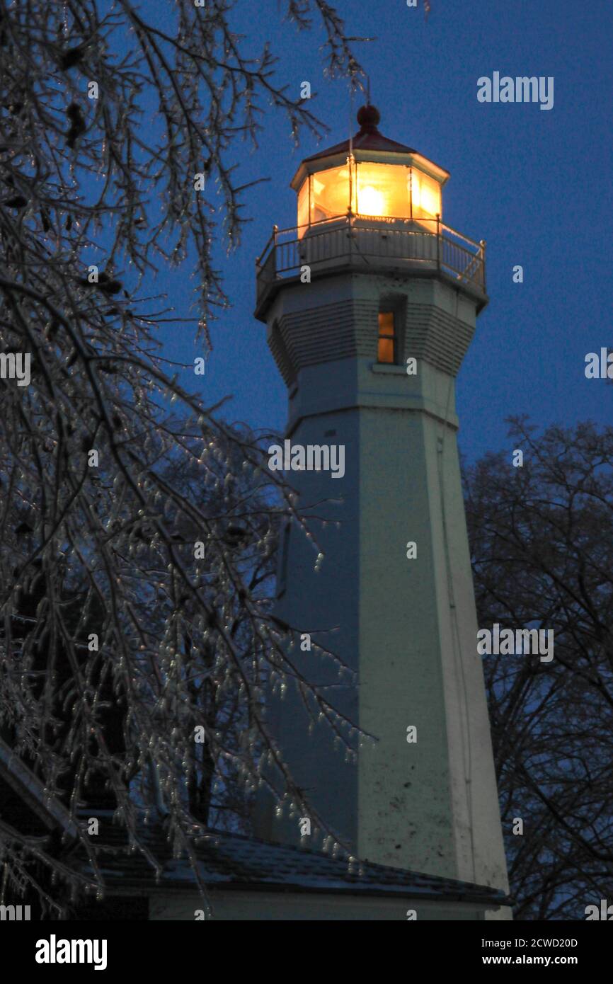 Port Sanilac, Michigan, Stati Uniti d'America - 12 dicembre 2013: Faro illuminato del faro di Port Sanilac circondato da cicliche in una fredda notte invernale. Foto Stock