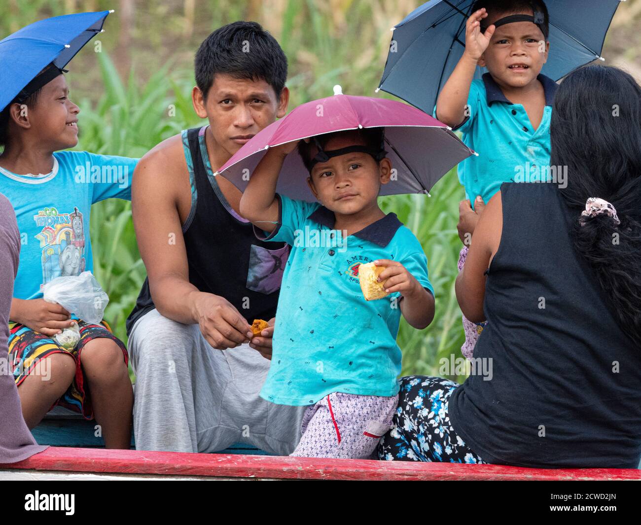 Una famiglia che indossa i cappelli da pioggia a Yarapa Caño, Río Ucayali, riserva di Pacaya-Samiria, Perù. Foto Stock