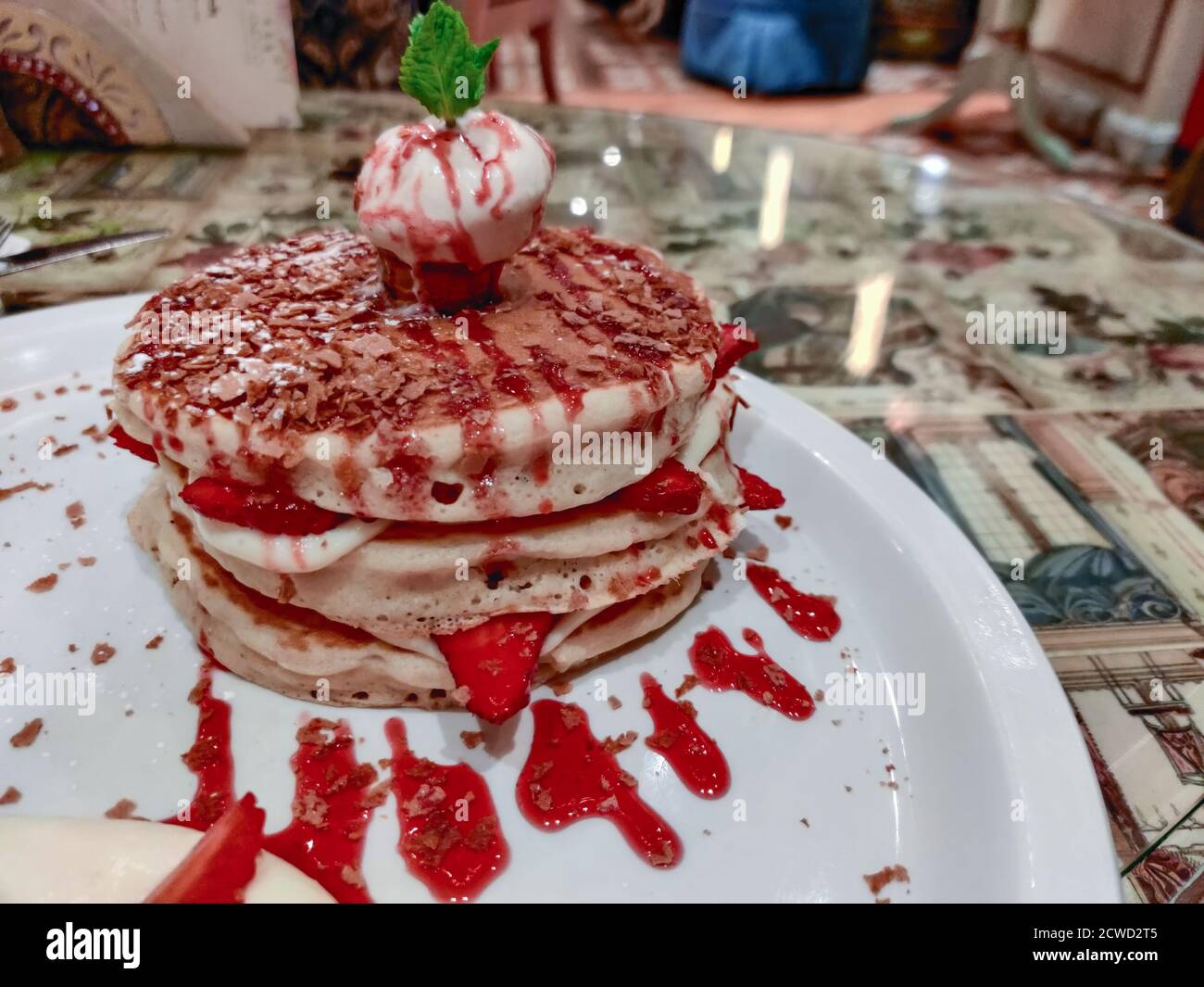 Primo piano di dessert servito in un ristorante elegante | Frittelle alla fragola e alla vaniglia con un cucchiaio per gelato Foto Stock