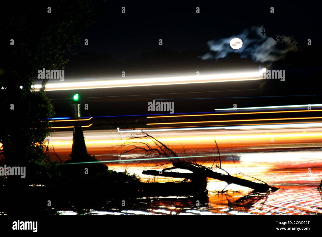 Esposizione notturna composta da una chiatta che passa su Fiume Mississippi a mezzanotte con una luna piena Foto Stock