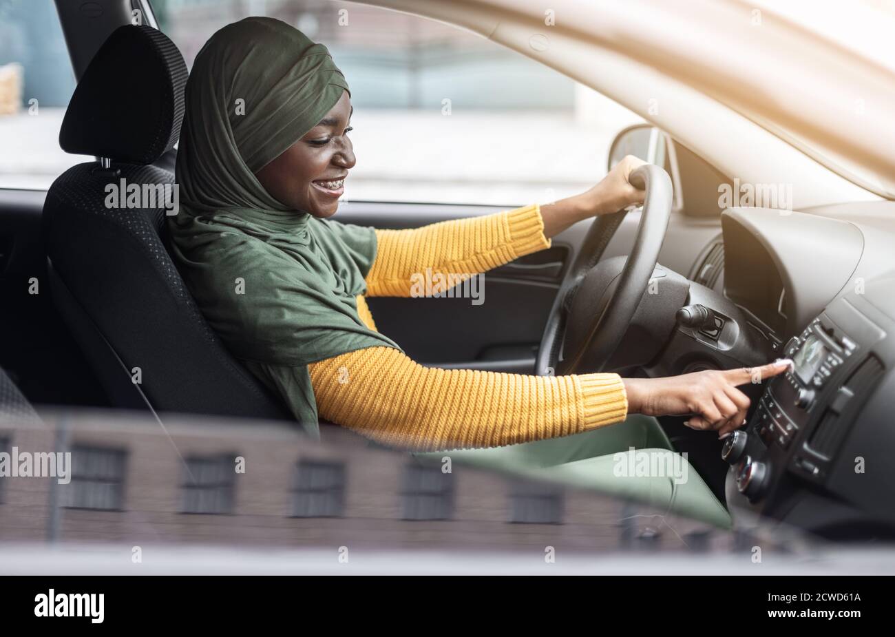 Playlist auto. Gioiosa donna musulmana nera che guida l'automobile e ascolta la musica Foto Stock