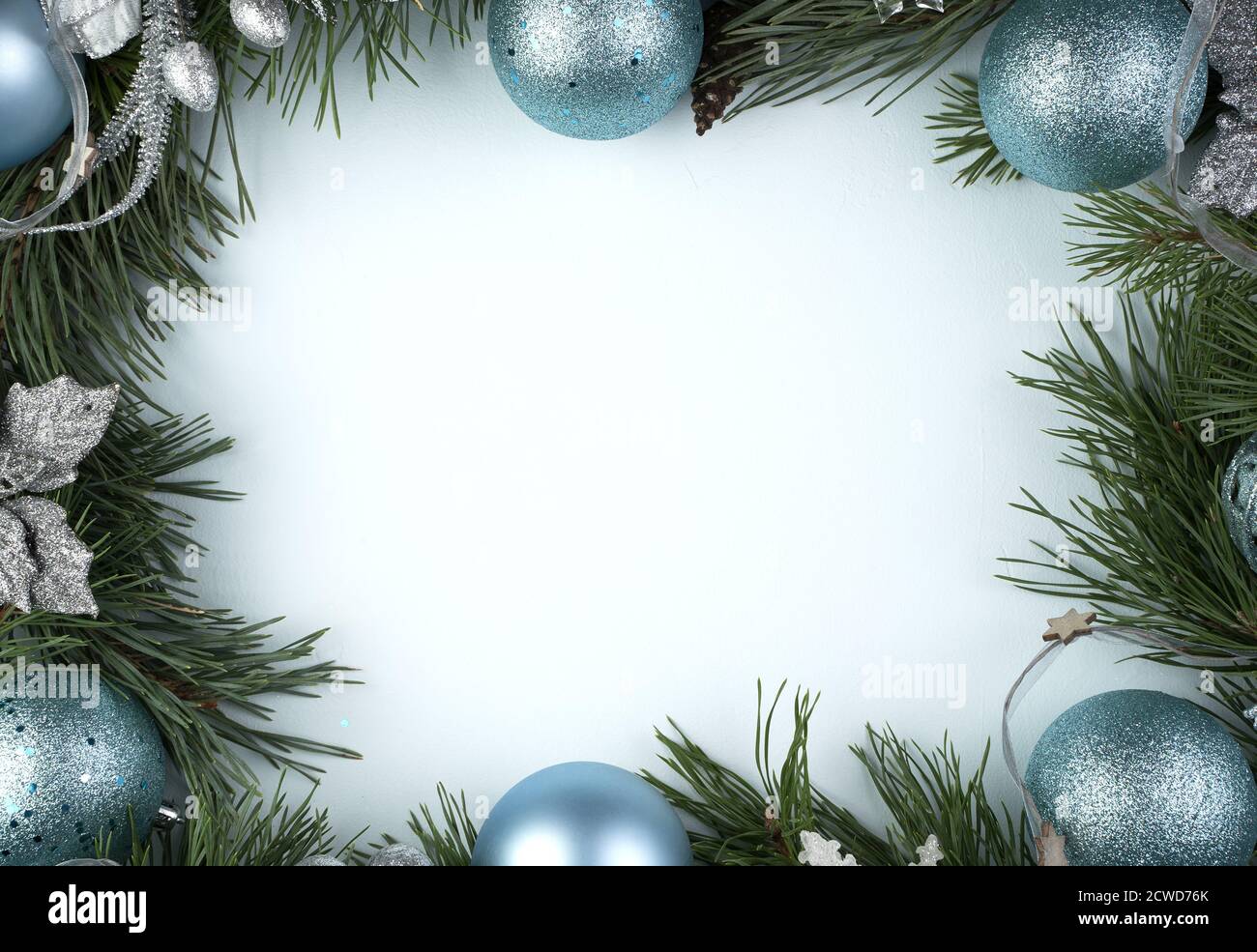 Decorazioni blu natalizie e rami di pino su sfondo blu. Foto Stock