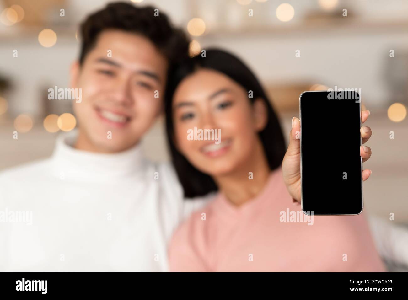 Coppia asiatica che mostra schermo del telefono vuoto Pubblicità Mobile Application Indoor Foto Stock